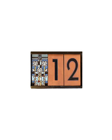 Decorative house number sign with colorful design and numbers on a white background